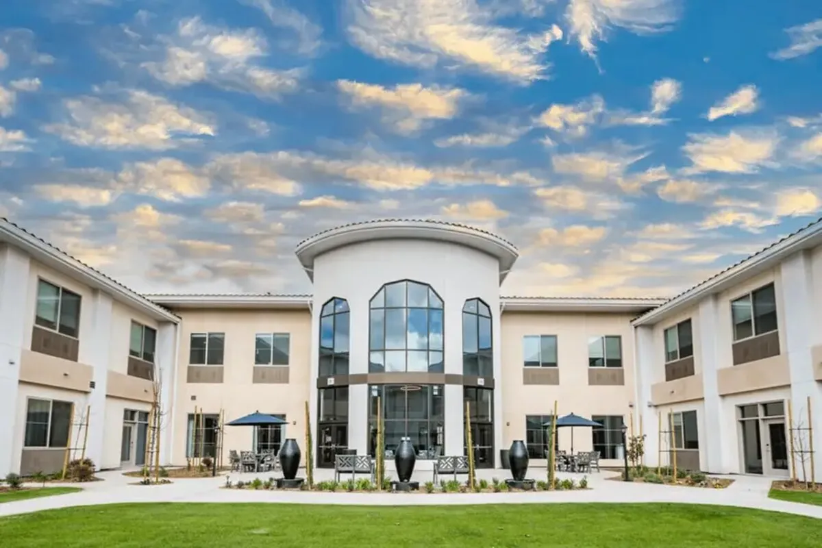 A senior-living community building with a glass atrium entrance at dusk