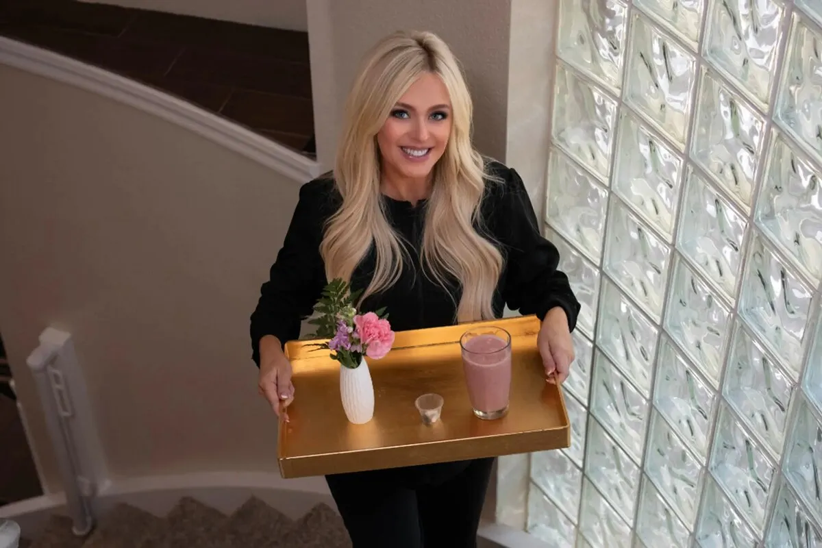 An in-home caregiver carrying a serving tray through a living room
