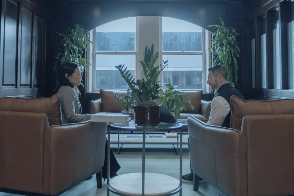 Two people meeting in a wood-panelled office overlooking a city skyline