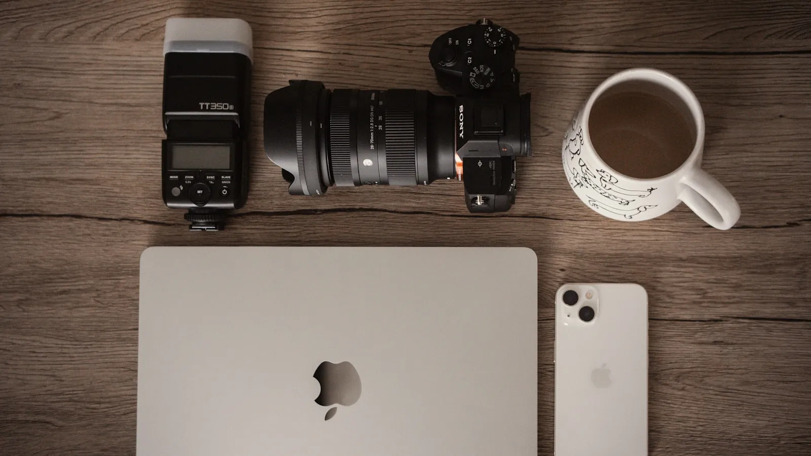 A content-creation flat lay with a camera, laptop and phone